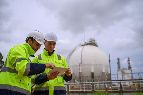 Blue collar workers are working at refinery factory. Heavy industry and engineering.
