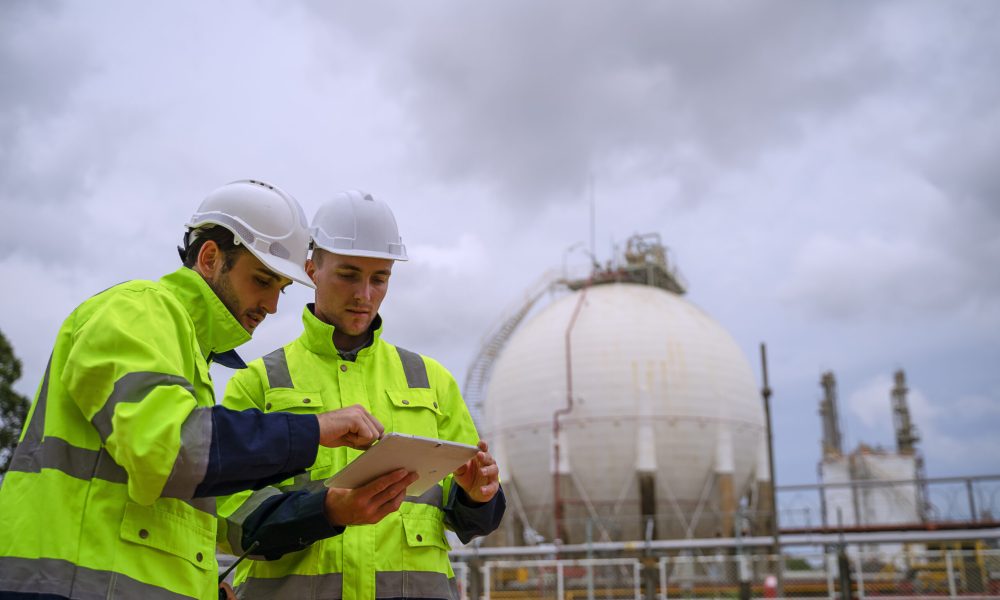 Blue collar workers are working at refinery factory. Heavy industry and engineering.