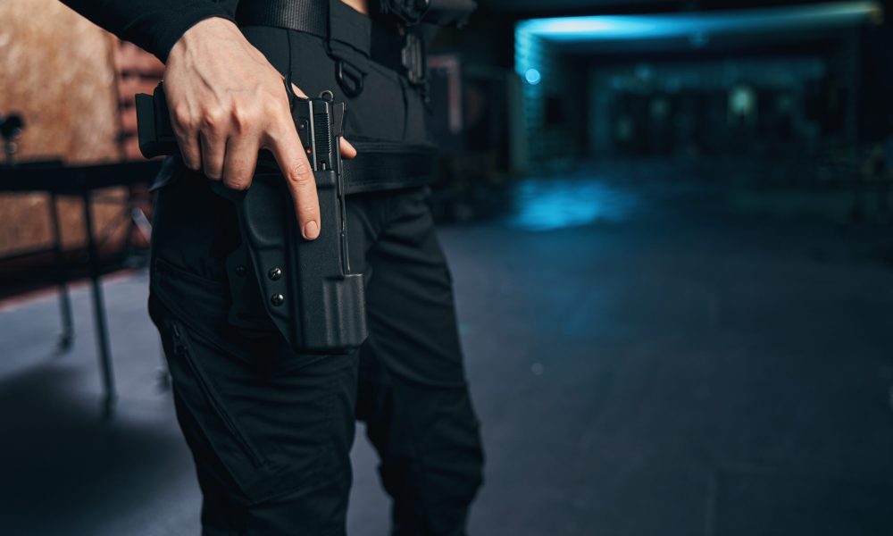 Cropped photo of a female with a loaded gun in her hand standing at an indoor shooting range