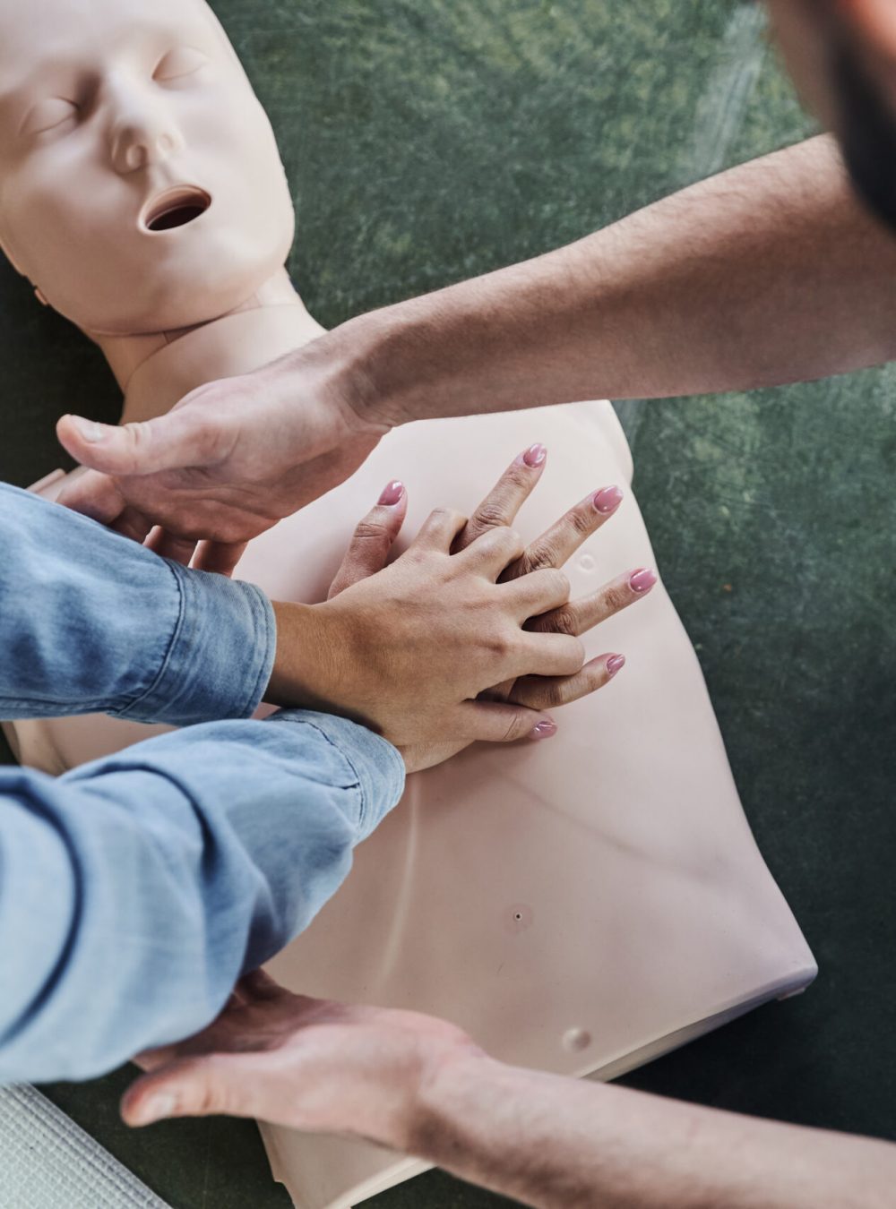 top view of young woman practicing chest compressions on CPR manikin during hands-on learning on